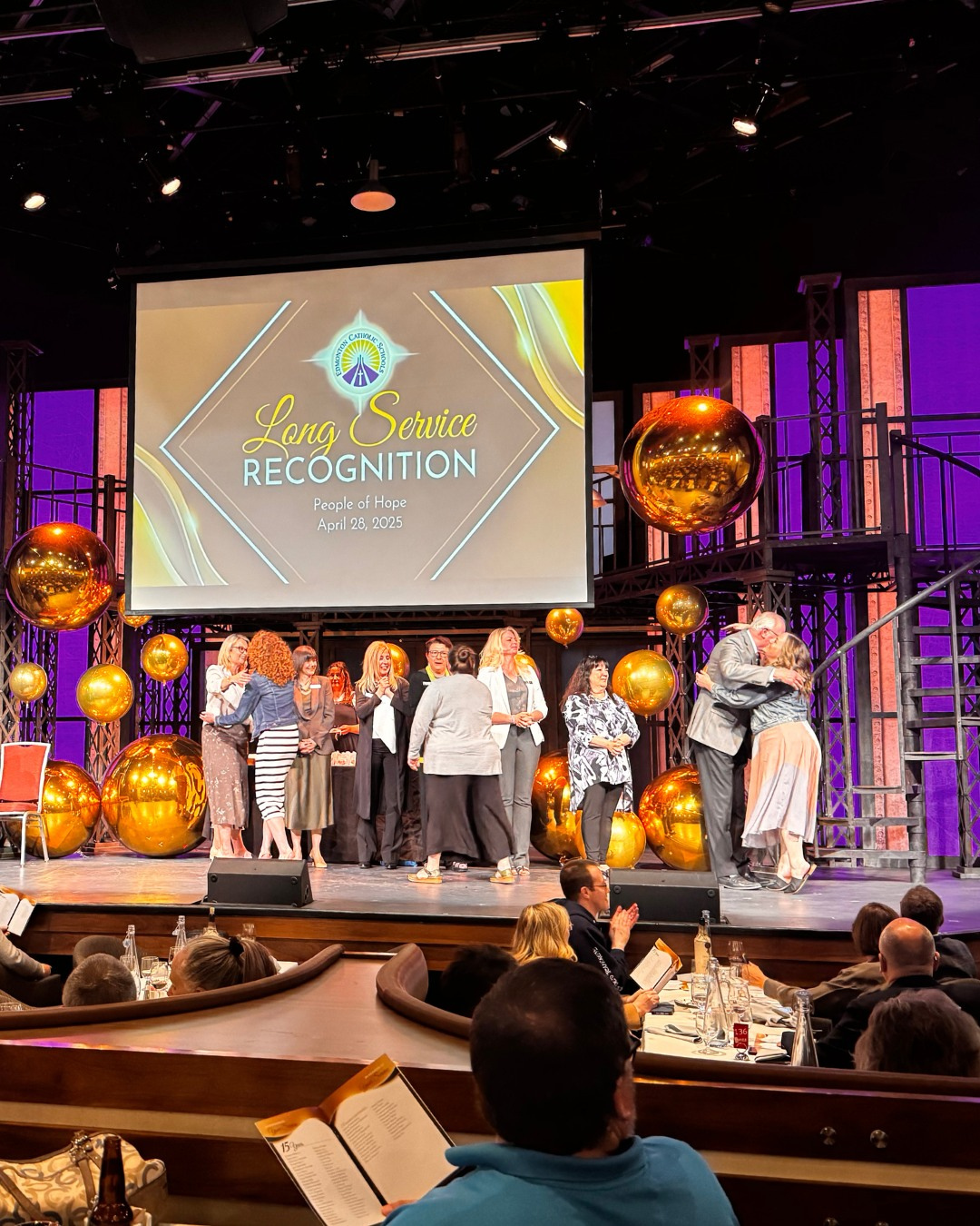 Wide shot of the trustees congratulating staff at the long service awards