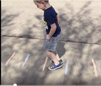 Student jumping over chalk lines outside