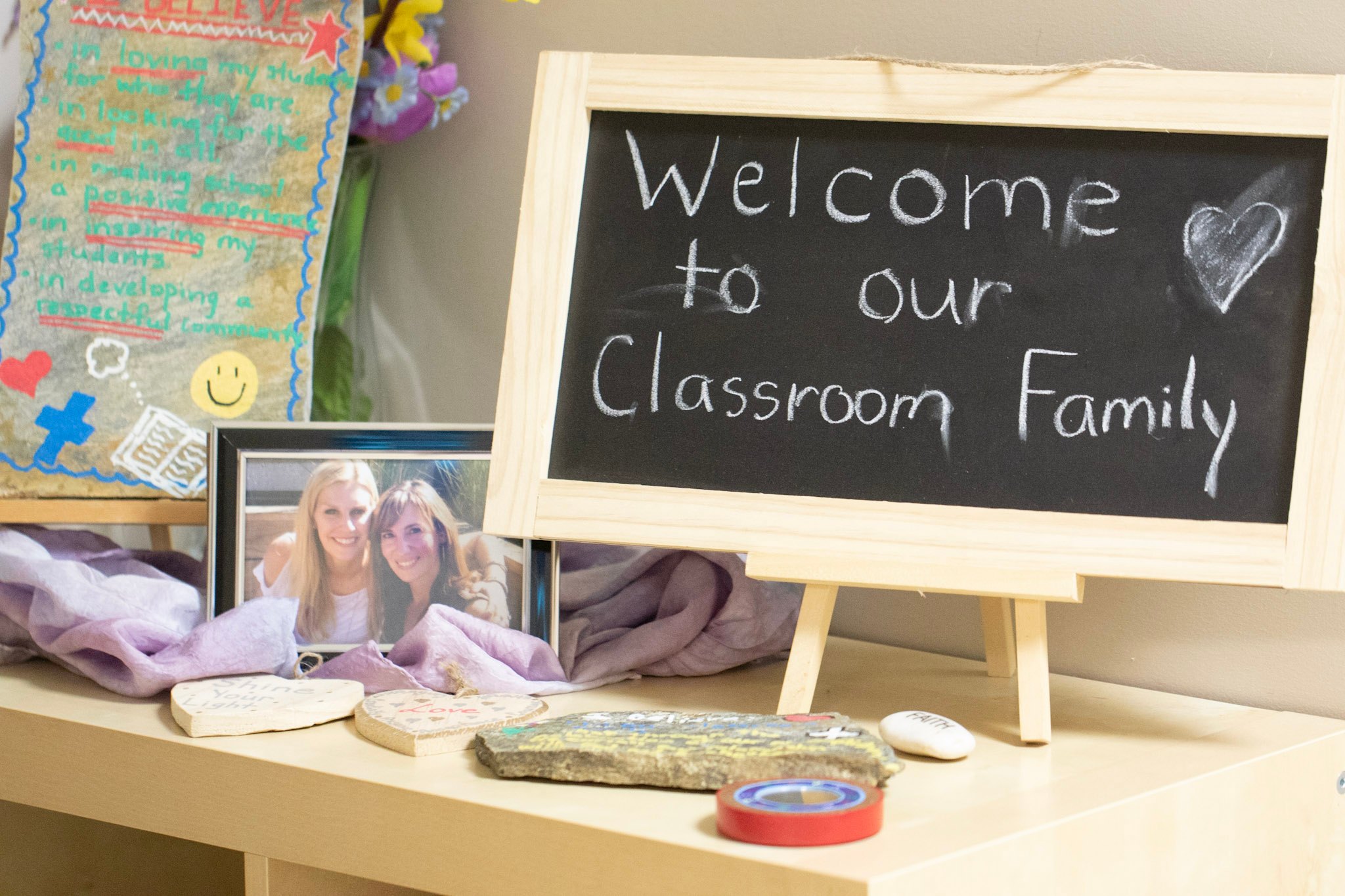 Image that has a photo of teachers in frame, small easel chalkboard that says Welcome to our Classroom Family